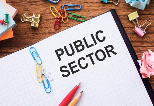 Public Sector in black letters on a school book with pencils 